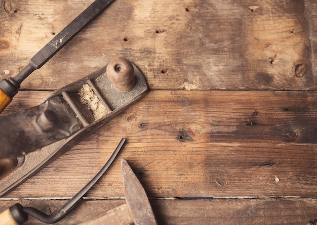 Od vintage hand tools on wooden background. Carpenter workplace.  Tinted photo