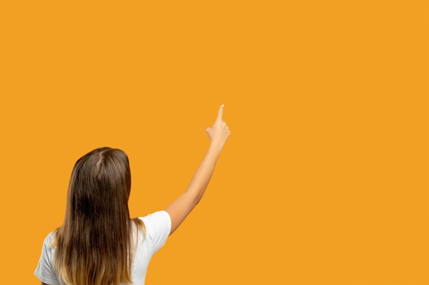 Offer promotion Advertising background Sale discount Teen girl showing presenting pointing finger at invisible product information text isolated on orange copy space