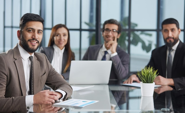 Office days group of business people sitting together at a table and looking at the camera