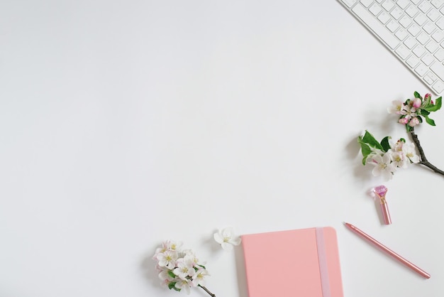 Office desk notepad keyboard apple flowers on a white background Minimal business concept for women