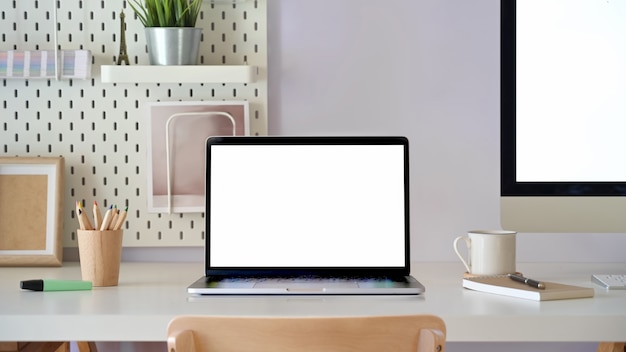 Office desk scenery with mockup blank screen laptop computer. Workspace minimal