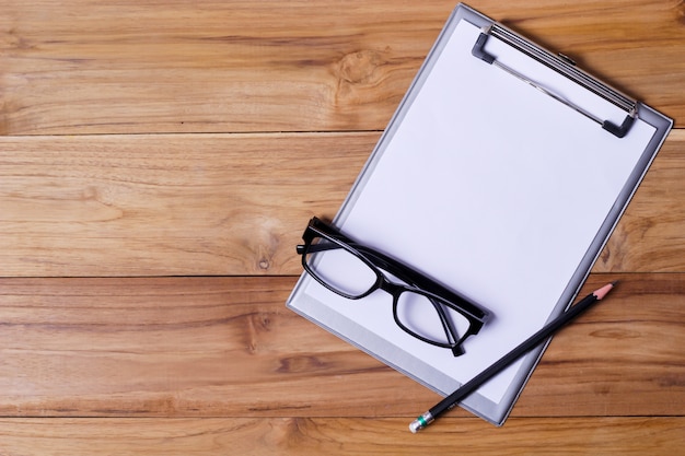 Office desk table with eye glasses short notepaper, pen and smartphone.