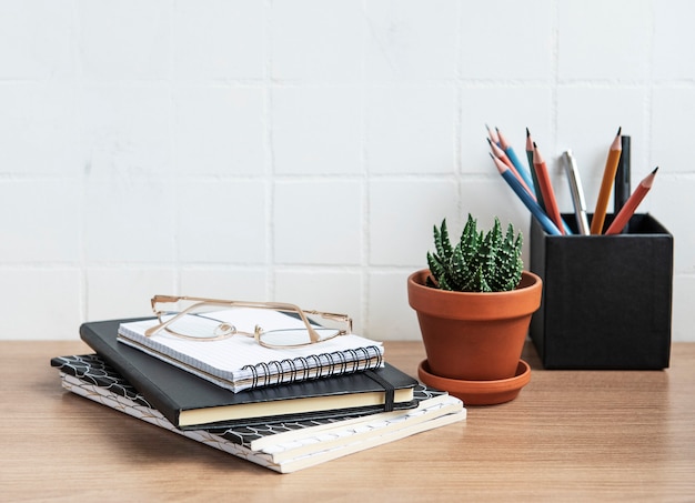 Office desk table with  notebooks, supplies and houseplants