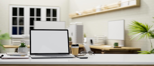 Office desk tabletop with laptop mockup and copy space over blurred office background