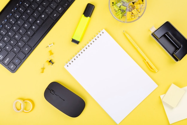 Office desk with computer and stationery, yellow background.