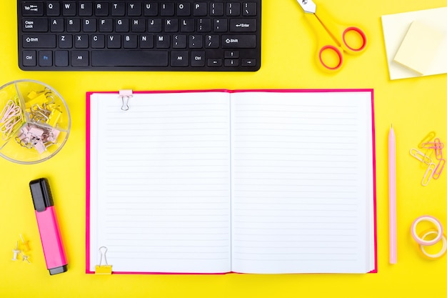 Office desk with computer and stationery, yellow background.