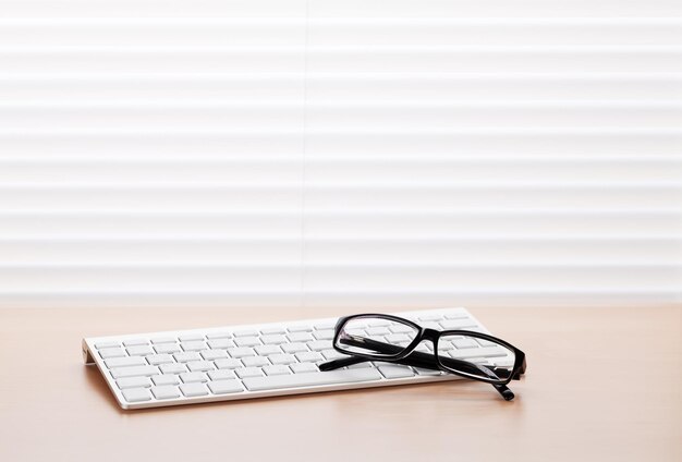 Office desk with pc keyboard and glasses