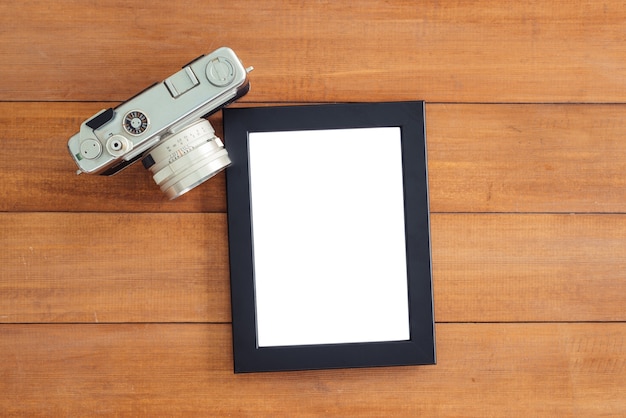 Office desk wooden table with old camera and poster mockup template. Top view with copy space