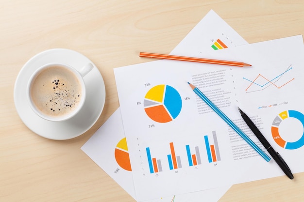 Office desk workplace with coffee and charts