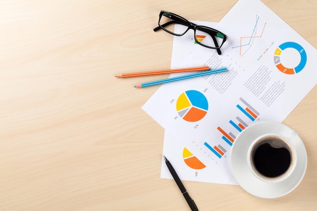 Office desk workplace with coffee and charts