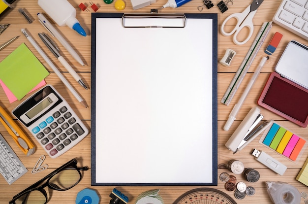 Office desk workplace with office or school supplies with blank paper in the center.