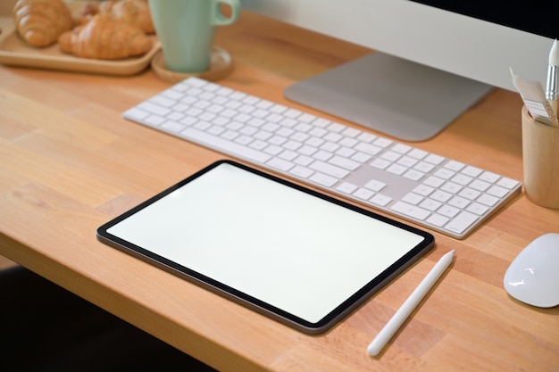 Office desk workspace with blank screen tablet and office supplies