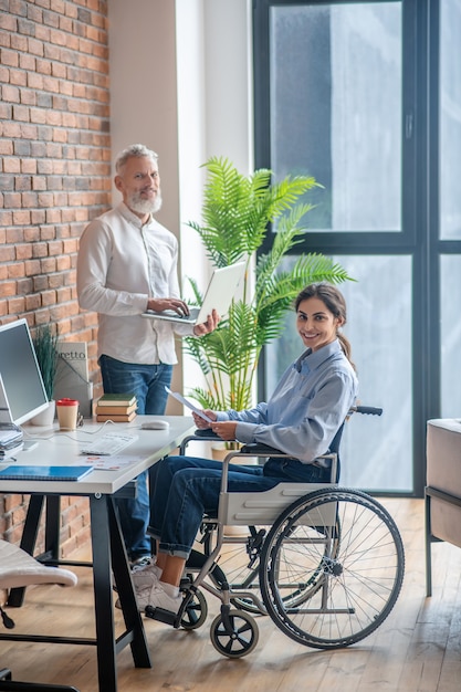 In the office. Handicapped young woman sitting at the table in the office