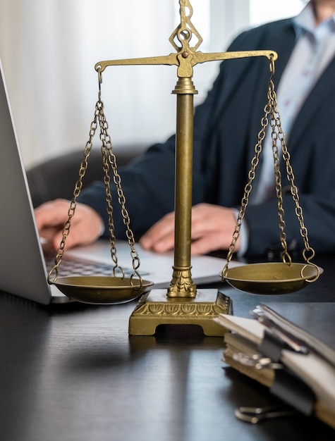 Photo office of lawyer with scales, laptop and documents on the workplace.