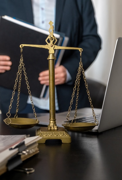 Office of Lawyer with Scales, laptop and documents on the workplace.