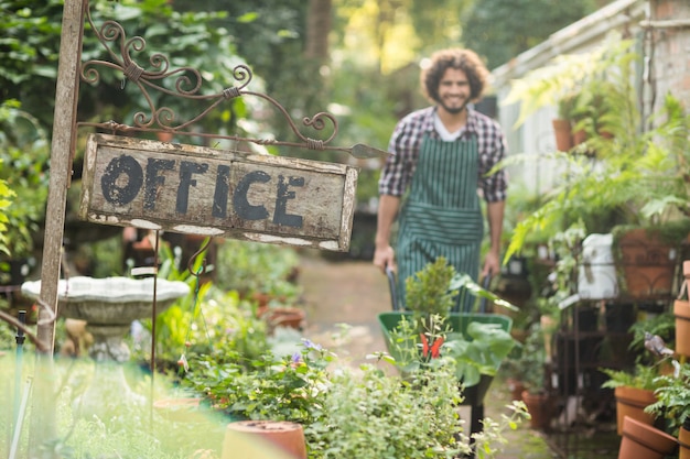 Office placard by plants while gardener in background