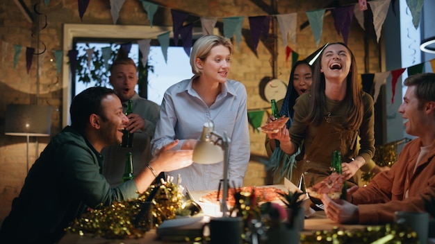 Office staff celebrating birthday at workplace with decorations clinking beer