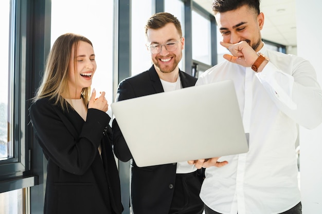 Office staff laughing while looking at a laptop