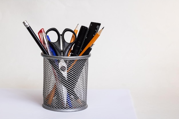 Office supplies in metal stand on gray background