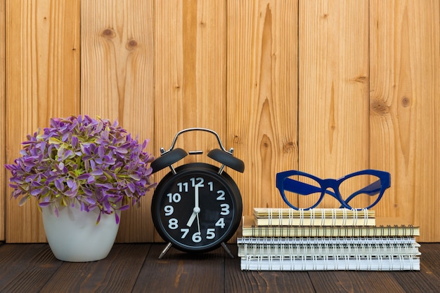 Office supplies tools items, notebook and alarm clock on wood.