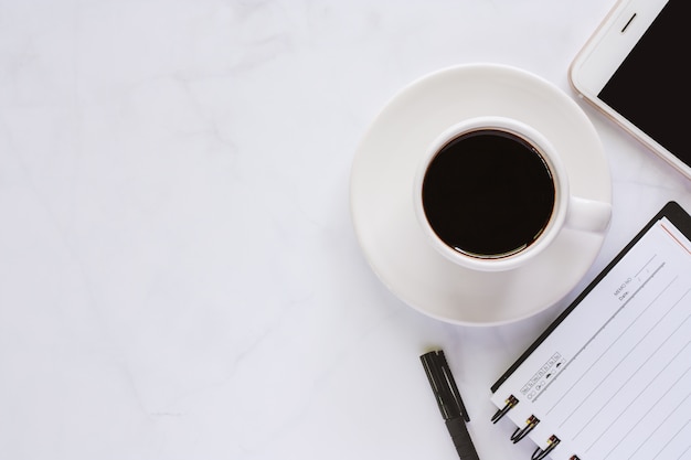 Office supplies with spiral notebook, pen, cup of coffee and smartphone