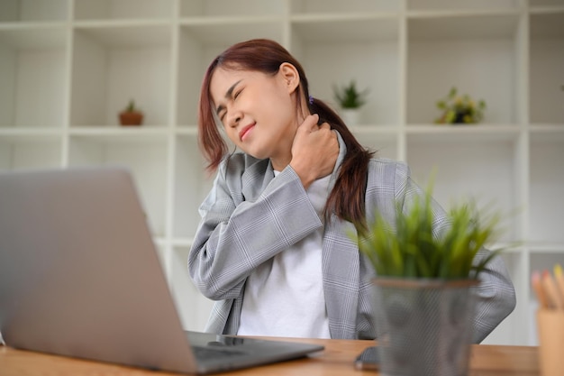 Photo office syndrome concept millennial asian businesswoman having a shoulders pain