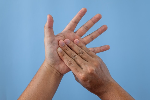 Office syndrome concept Palm of hands are massaged after working by fingers Close up shot isolate on blue background