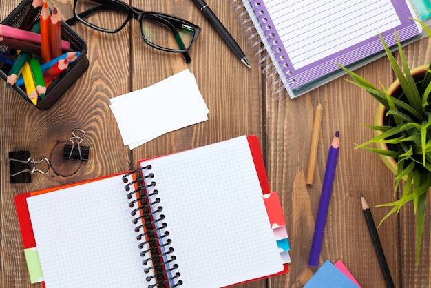 Office table with blank notepad and supplies. View from above with copy space