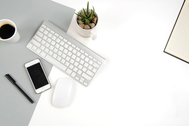 Office table with  keyboard, mouse, and smartphone on modern two tone (white and grey) bac