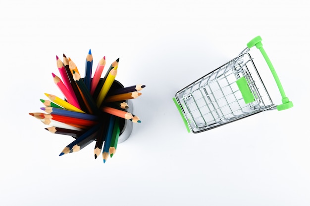 Office Tools In A Shopping Cart. Online shopping concept. Cart and pencils on white