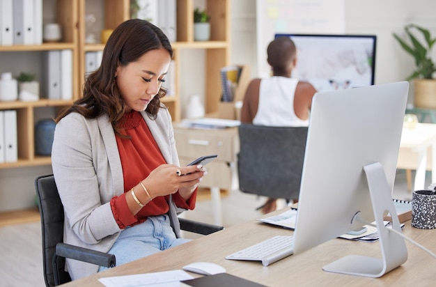 Office woman desk and reading phone message and communication while working in corporate building Young business executive and professional workplace girl looking at text on smartphone