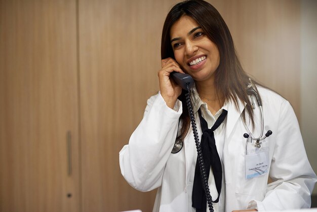 Photo office woman and smile on doctor with phone call for patient consultation or conversation on results female person healthcare and happy with communication for medical solution and advice at clinic