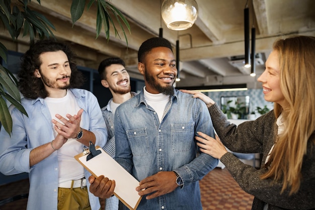 Office work team greeting their new african american male employee