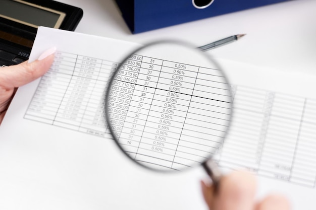 An office worker examines documents through a magnifying glass