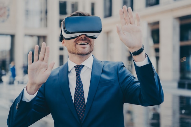 Office worker in formal suit exploring virtual world with VR glasses while relaxing outdoors