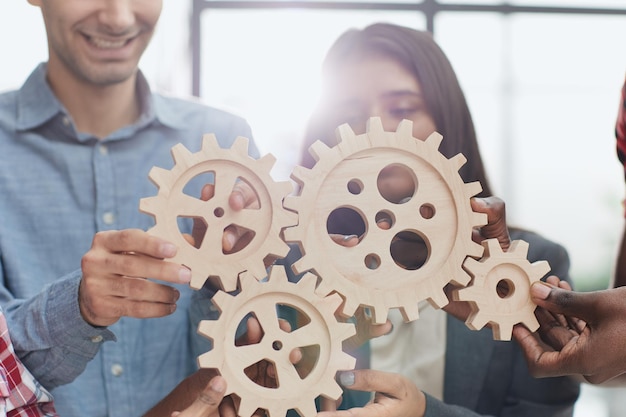 Office worker holding cog wheel as unity and teamwork in corporate workplace concept