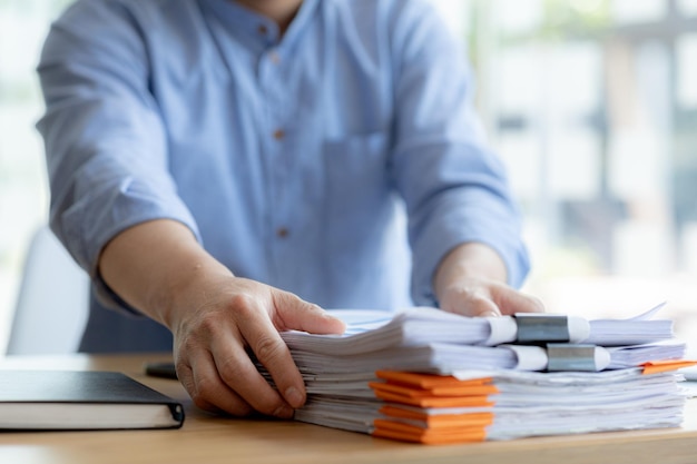 The office worker is working at the company he is tidying up the paperwork on his desk to start working on the paperwork he is in the finance department and is preparing the financial statements