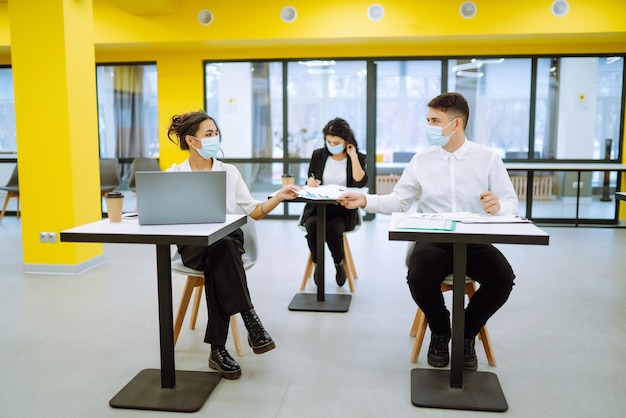 Office worker wearing face mask for social distancing for virus prevention while using laptop