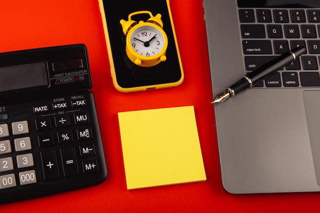 Office workplace with laptop, clock and smartphone