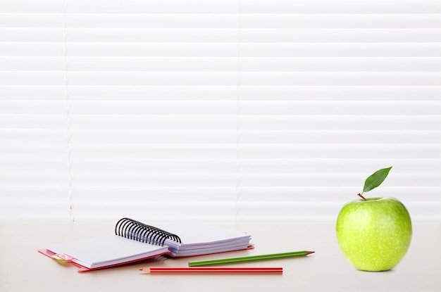 Office workplace with supplies and apple