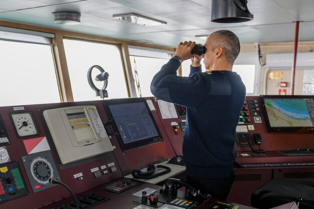 Officer on watch with binoculars on the navigational bridge