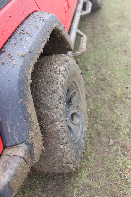 Offroad car wheel covered with wet dirt on ground road at countryside travelling by suv