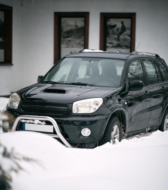 Offroad vehicle parked during snowfall Concept of using compact all wheels drive SUV in winter