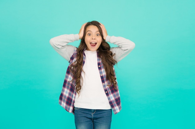 Oh my god. child wear trendy casual jacket. kid spring and autumn fashion. little beauty. express positive emotions. happy small girl turquoise background. surprised schoolgirl has long curly hair.