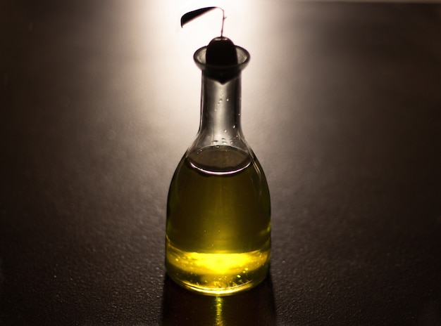 Oil bottle with olive with black background