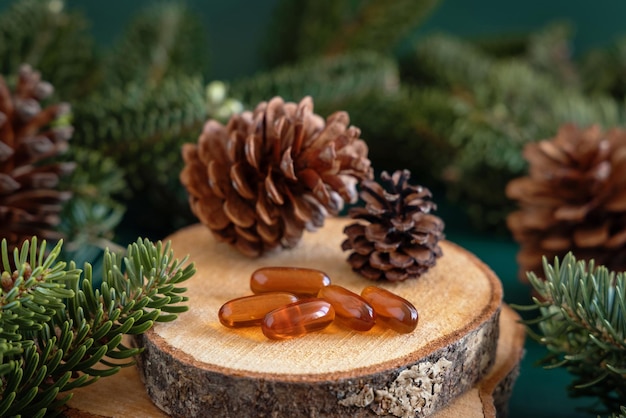 Oil capsules near fir branches and pine cones close up Taking dietary supplements