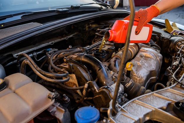 Oil change in car service. Hand in protective glove with oil bottle