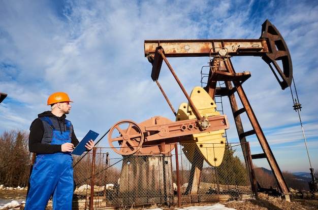 Oil man checking work of oil well pump jack