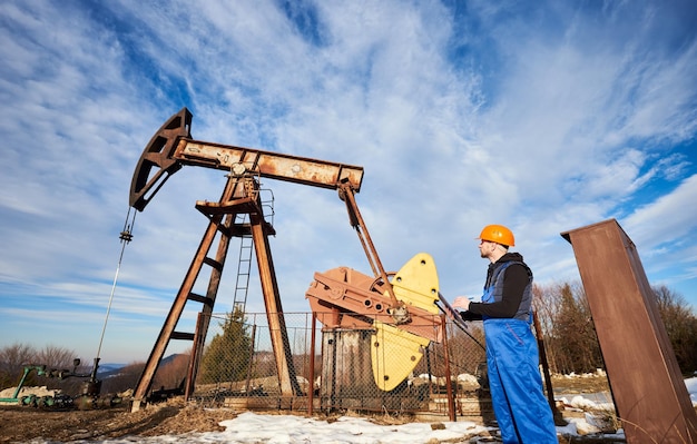 Oil man checking work of oil well pump jack