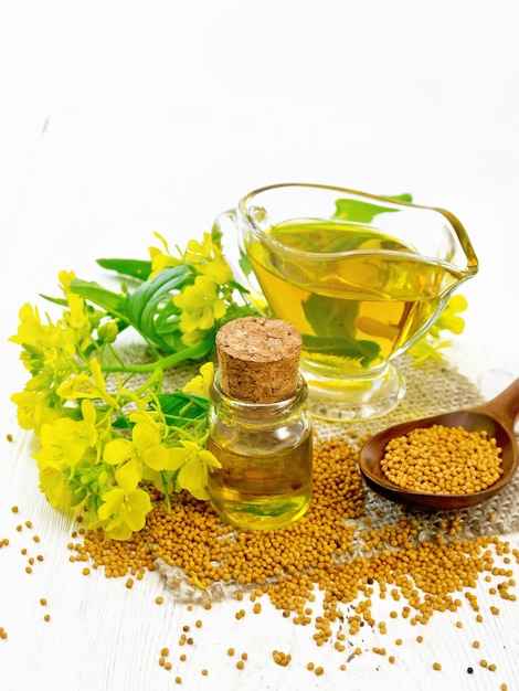 Oil mustard in jars and gravy boat on wooden board